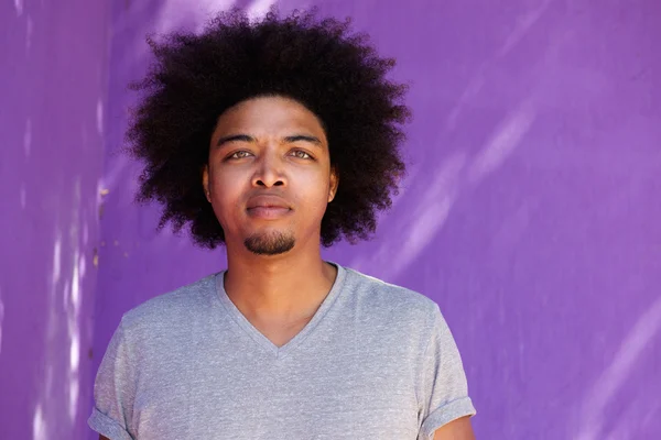 Pemuda afro berdiri melawan latar belakang ungu — Stok Foto
