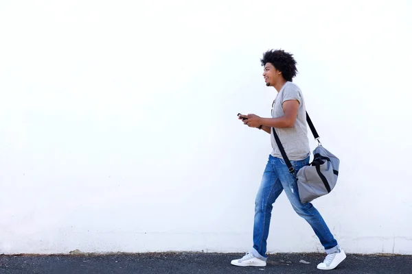 Jovem caminhando com saco e celular — Fotografia de Stock