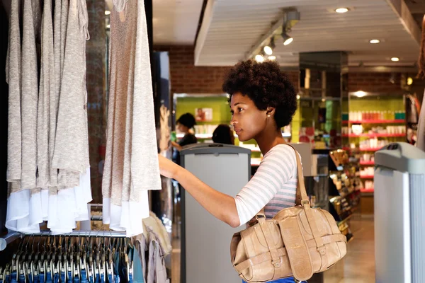 Hermosa mujer buscando ropa en la tienda — Foto de Stock