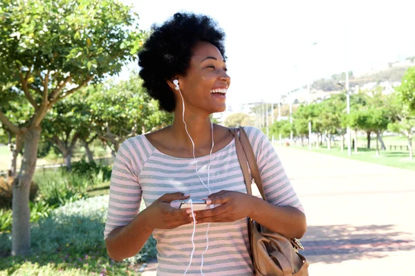 Lachende vrouw wandelen in het park met koptelefoon — Stockfoto