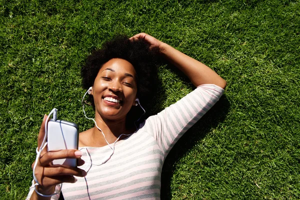 Frau liegt im Gras und hört Musik — Stockfoto