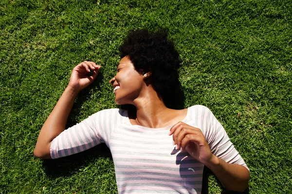 Lachende vrouw liggend in het gras in de zomer — Stockfoto