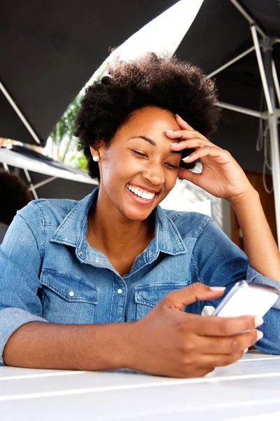 Lachende vrouw zitten buiten met behulp van mobiele telefoon in café — Stockfoto