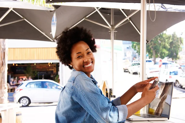 Donna sorridente con computer e cellulare al caffè — Foto Stock