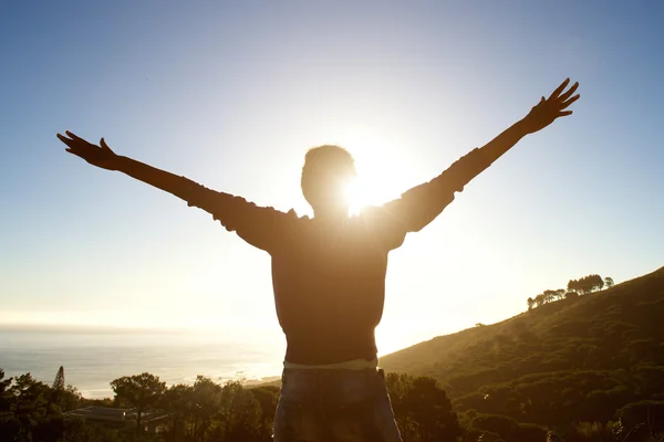 Femme écartant les bras profitant du coucher du soleil — Photo