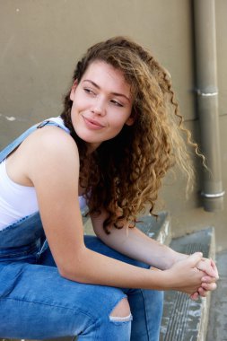 Basamaklarda oturup gülümseyen genç kız 