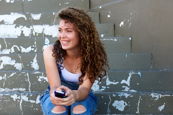 ยิ้มสาววัยรุ่นถือโทรศัพท์ — ภาพถ่ายสต็อก