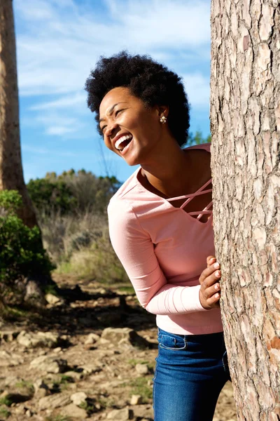 Beautiful woman standing behind a tree — Stock Photo, Image