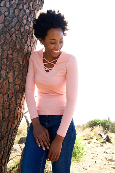 Aantrekkelijke jonge Afrikaanse vrouw leunt aan een boom — Stockfoto