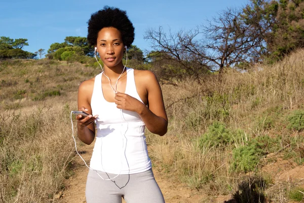 Healthy young female runner listening to music — Stock Photo, Image