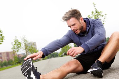 Erkek koşucu streç yapıyor oturuyor