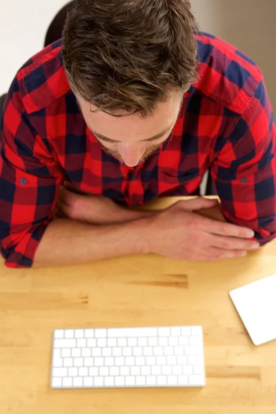 Man zit aan bureau met toetsenbord denken — Stockfoto