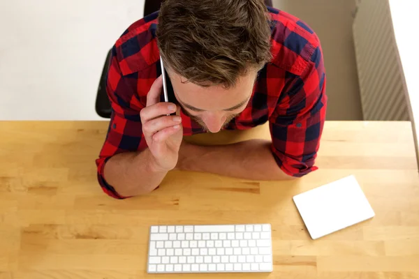 Man zit bij balie praten op mobiele telefoon — Stockfoto