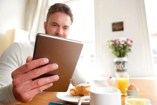 Oudere man bedrijf tablet tijdens het ontbijt — Stockfoto