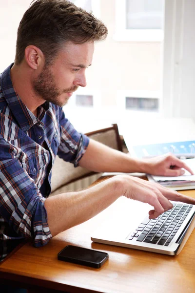 Medelålders man tänka och pekar på laptop — Stockfoto