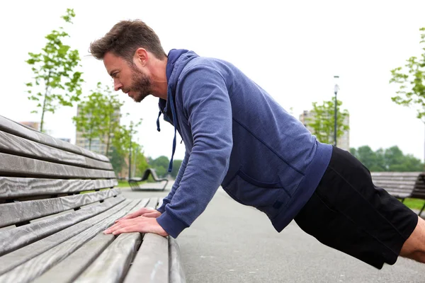 Bonito homem fazendo flexões no banco — Fotografia de Stock