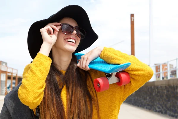 Usměvavá mladá žena držící skateboard — Stock fotografie