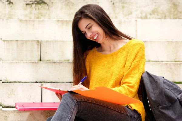 Lachende student het maken van notities — Stockfoto