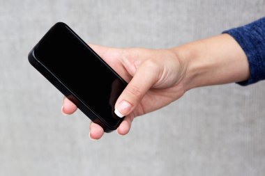 Kadın el cep telefonu gri duvara kullanarak