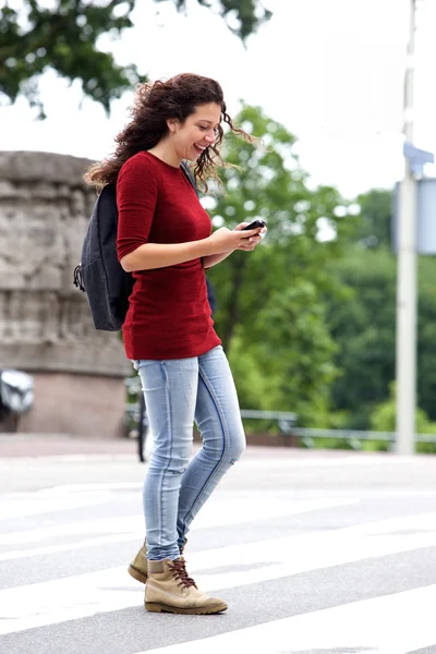 Женщина, переходящая улицу с мобильным телефоном — стоковое фото