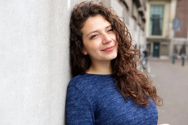 Jovem mulher encostada a uma parede — Fotografia de Stock