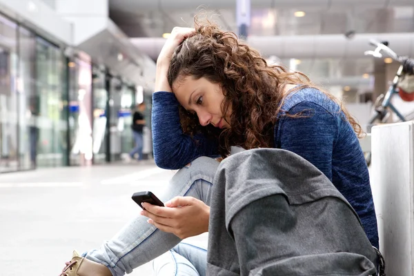 Wanita muda duduk dan menggunakan telepon — Stok Foto