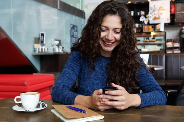 Vrouw zitten in café met mobiele telefoon — Stockfoto