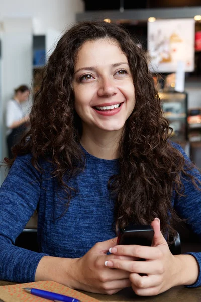 Женщина сидит в кафе с мобильным телефоном — стоковое фото