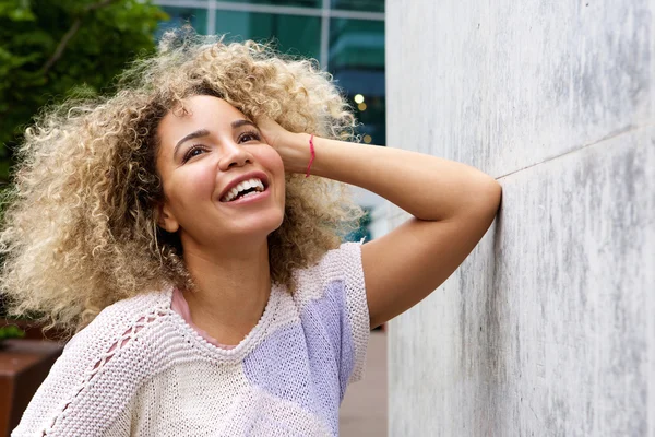 Woman leaning on wall with hand in hair — Stock Photo, Image