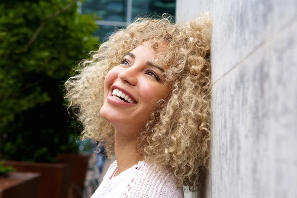 Heureuse jeune femme penchée sur le mur — Photo