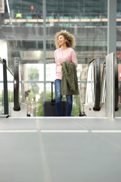 Mladá žena s kufrem na eskalátoru — Stock fotografie
