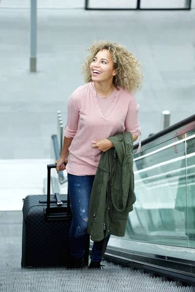 Женщина, стоящая на эскалаторе с чемоданом — стоковое фото