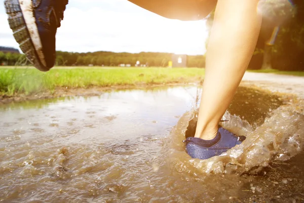 泥の水たまりにランナーの足 — ストック写真