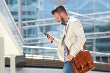 Cep telefonu kullanarak çanta ile gülümseyen olgun adam