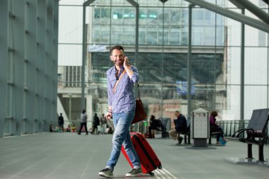 Tren istasyonunda bir telefon ile yürüyen gülümseyen adam
