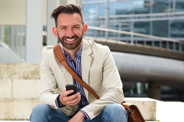 Зрелый мужчина улыбается с мобильником — стоковое фото