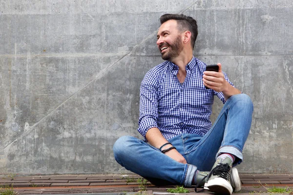 Веселый мужчина средних лет с мобильным телефоном — стоковое фото
