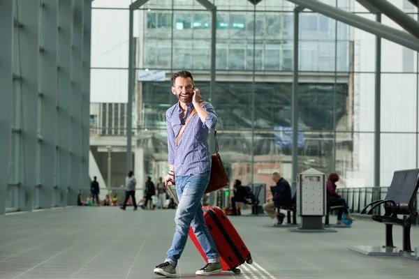 Tren istasyonunda bir telefon ile yürüyen gülümseyen adam — Stok fotoğraf