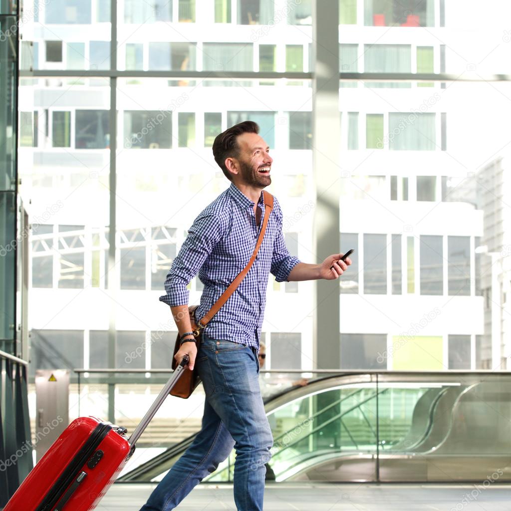 Smiling mature male traveler walking with suitcase