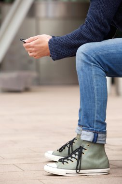 Açık havada telefon kullanarak oturan adam