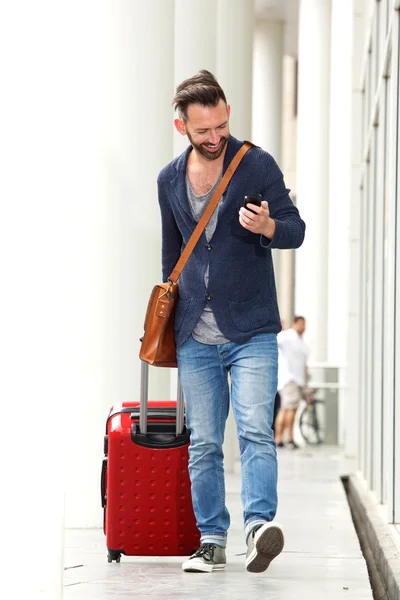 Feliz hombre moderno enviando mensaje de texto en el aeropuerto — Foto de Stock