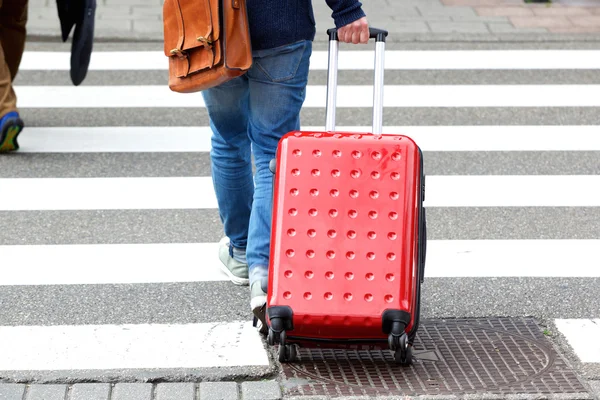 Человек, переходящий улицу с чемоданом — стоковое фото