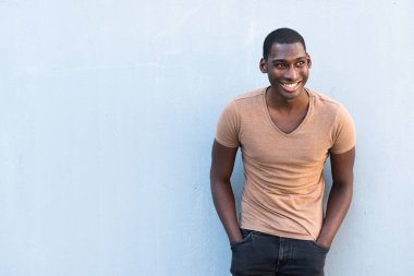 Yatay portre mutlu Afrikalı Amerikalı adam gri arka planda gülümsüyor ve başka tarafa bakıyor.