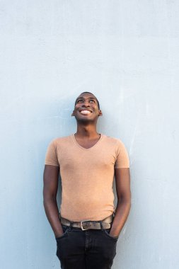 Duvara yaslanmış ve kafasını kaldırmış mutlu bir Afrikalı Amerikalı portre. 