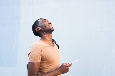 Cep telefonu ve kulaklıkları olan mutlu Afrikalı Amerikalı bir adam.