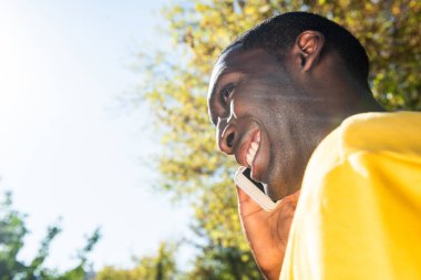 Yan portreyi kapat. Genç siyahi adam dışarıda cep telefonuyla konuşuyor.