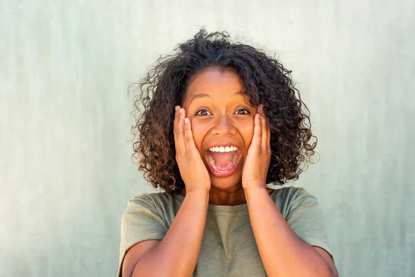 Close up portrait surprised young woman with hands on face and mouth open surprised expression