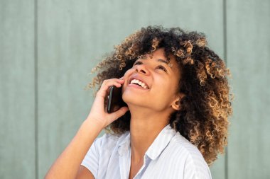 Kapalı portre genç Afrikalı Amerikalı kadın cep telefonuyla konuşurken gülüyor 