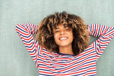 Kapalı portre gülümseyen Afrikalı Amerikalı kız ellerini başının arkasına koyup rahatlıyor.