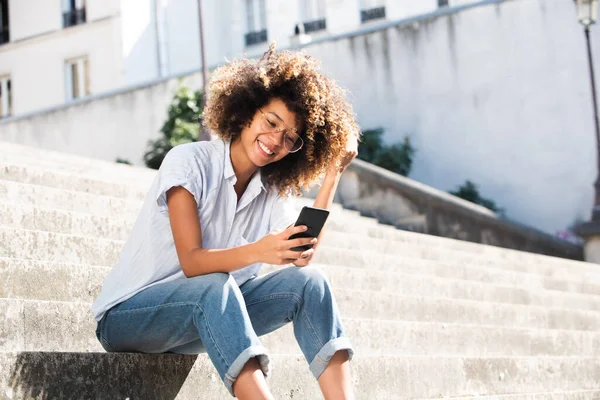 Retrato Sonriente Mujer Joven Con Anteojos Sentados Fuera Mirando Teléfono — Foto de Stock